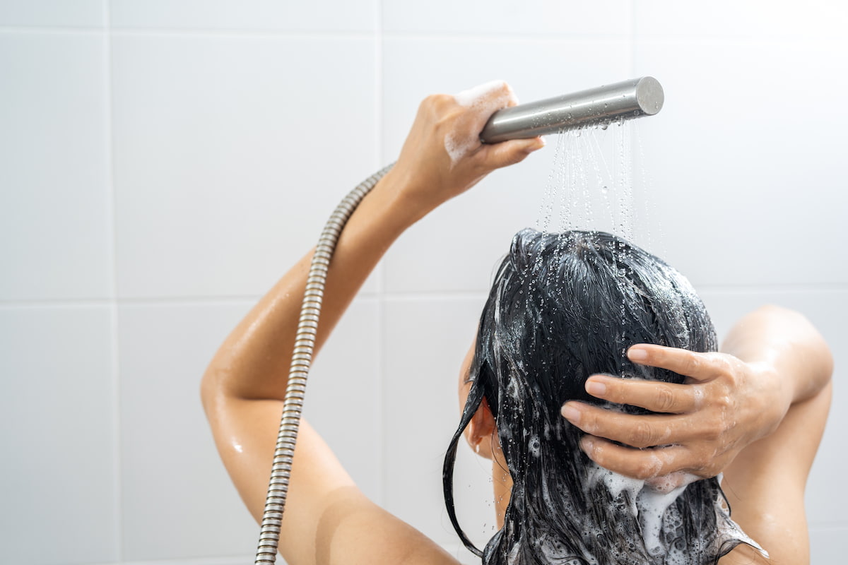 woman standing in the shower washing her hair woman standing in the shower washing her hair