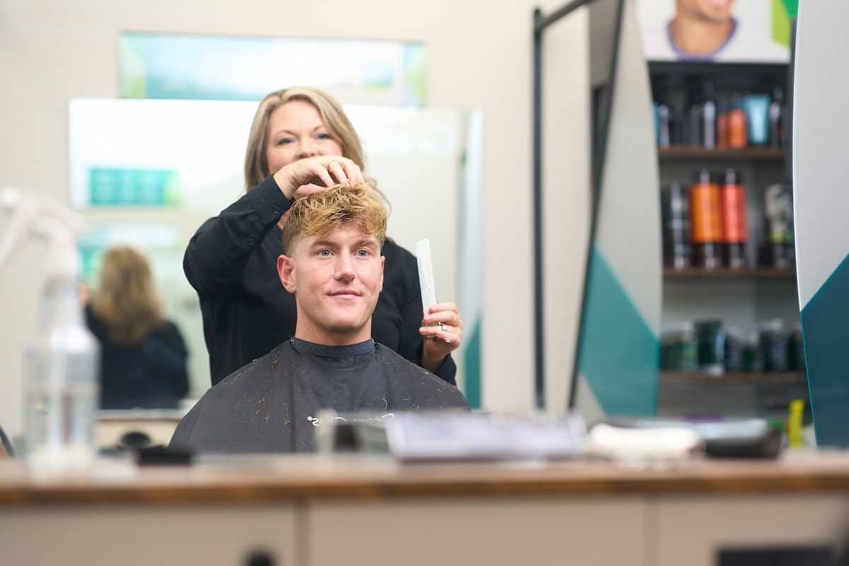 Blonde haired male getting his hair styled in a salon chair Blonde haired male getting his hair styled in a salon chair