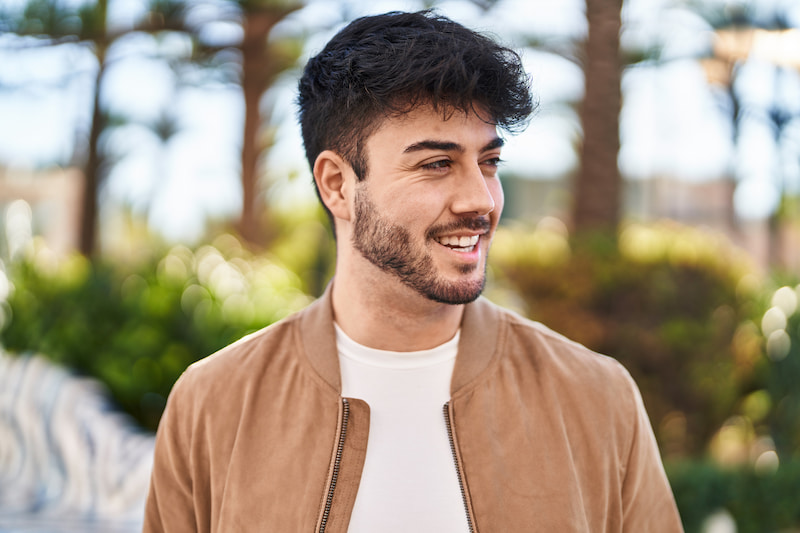A man in a brown jacket smiling off to the side. A man in a brown jacket smiling off to the side.